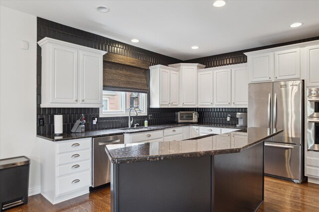 46746 Merion Cir, Northville, MI 48168 - kitchen with appliances with stainless steel finishes, white cabinets, dark wood-type flooring, decorative backsplash, and a kitchen island