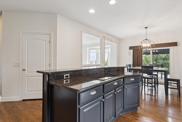 46746 Merion Cir, Northville, MI 48168 - kitchen with black electric cooktop, a chandelier, dark wood-style floors, a center island, and dark stone counters