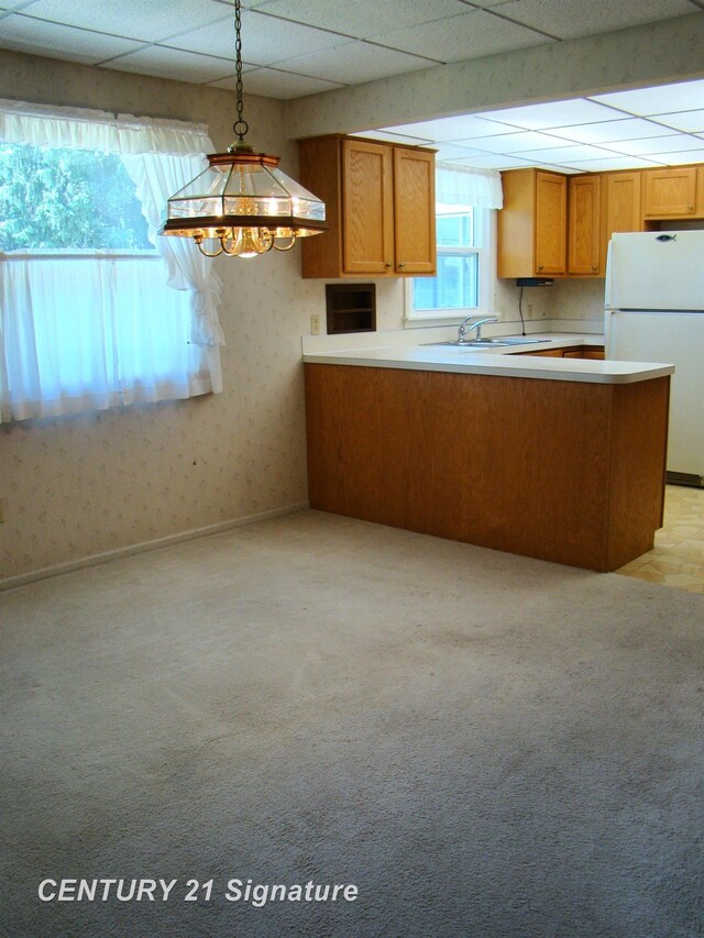4215 S Wayside Dr, Saginaw, MI 48603 - kitchen with freestanding refrigerator, a paneled ceiling, brown cabinetry, a peninsula, and light countertops