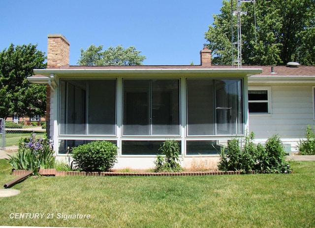 4215 S Wayside Dr, Saginaw, MI 48603 - view of property exterior featuring a chimney, a sunroom, and a yard