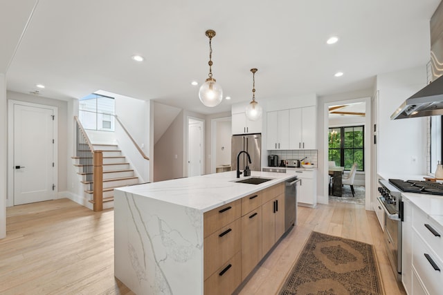 1053 Canterbury St, Birmingham, MI 48009 - kitchen featuring stainless steel appliances, light wood-style floors, wall chimney exhaust hood, recessed lighting, and an island with sink