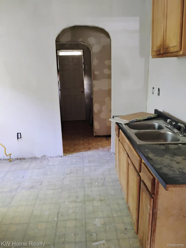 12749 Washburn St, Detroit, MI 48238 - kitchen with arched walkways, light floors, dark countertops, and brown cabinetry