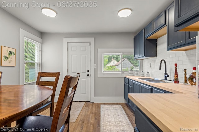 3917 Bewick St, Detroit, MI 48214 - kitchen featuring butcher block countertops, light wood finished floors, backsplash, and blue cabinetry