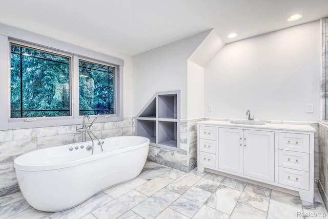 2685 Fry Rd, Highland, MI 48357 - bathroom featuring marble look tiles, a wainscoted wall, a freestanding tub, tile walls, and plenty of natural light