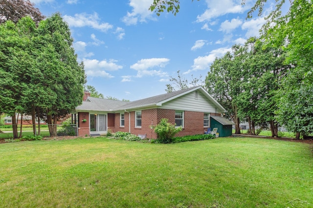 239 Heyn St, Saginaw, MI 48602 - view of front facade with brick siding, a chimney, and a front lawn