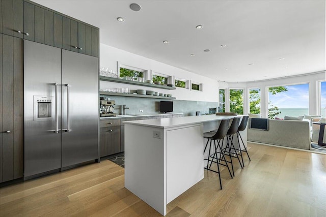 9182 Hemlock Ln, Bridgman, MI 49106 - kitchen with stainless steel built in fridge, light wood-type flooring, light countertops, open shelves, and a center island