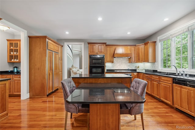 8356 Misty Mdws, Grand Blanc, MI 48439 - kitchen featuring a breakfast bar, paneled dishwasher, light wood-type flooring, a center island, and tasteful backsplash