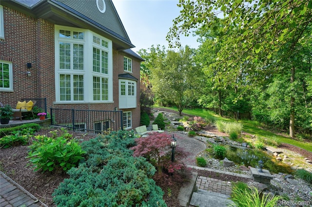 8356 Misty Mdws, Grand Blanc, MI 48439 - view of property exterior featuring brick siding and a small pond