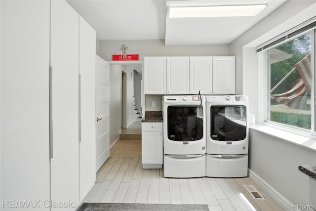 7027 Beverly Crest Dr, West Bloomfield, MI 48322 - laundry area featuring independent washer and dryer, cabinet space, and light wood-style flooring