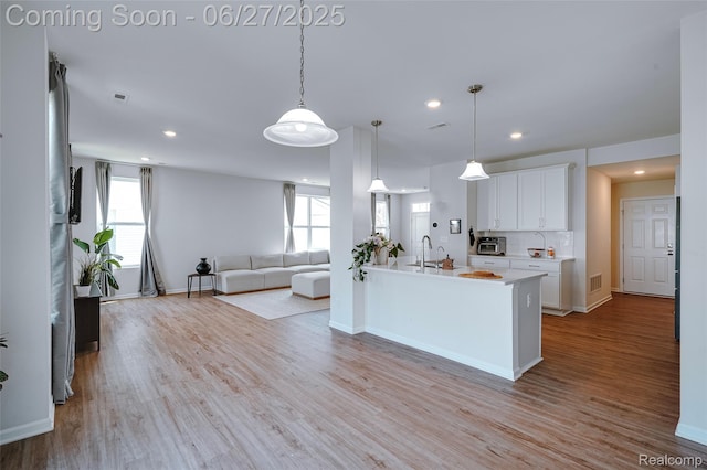606 Angus Ln, Saline, MI 48176 - kitchen featuring healthy amount of natural light, light countertops, light wood finished floors, white cabinets, and recessed lighting