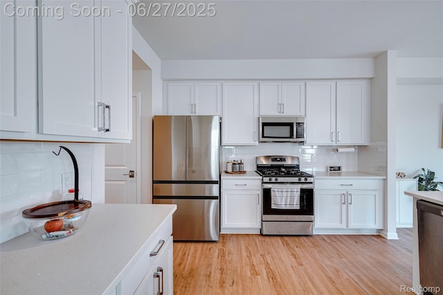 606 Angus Ln, Saline, MI 48176 - kitchen featuring stainless steel appliances, light countertops, white cabinets, and light wood-style flooring