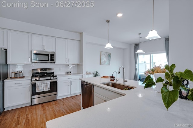 606 Angus Ln, Saline, MI 48176 - kitchen with appliances with stainless steel finishes, light countertops, backsplash, white cabinetry, and decorative light fixtures