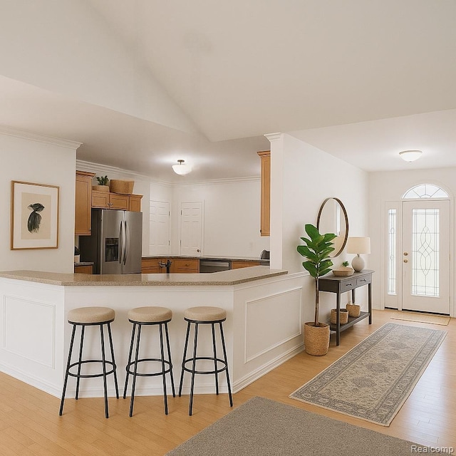 35260 Bradford Dr, New Baltimore, MI 48047 - kitchen featuring stainless steel appliances, a breakfast bar area, vaulted ceiling, light wood-style floors, and a peninsula
