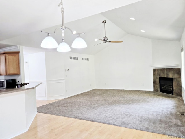 35260 Bradford Dr, New Baltimore, MI 48047 - kitchen with stainless steel microwave, vaulted ceiling, open floor plan, ceiling fan, and a tiled fireplace