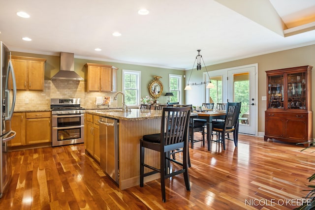 7150 Limerick Ln SW, Byron Center, MI 49315 - kitchen with stainless steel appliances, wall chimney exhaust hood, dark wood finished floors, light stone counters, and ornamental molding