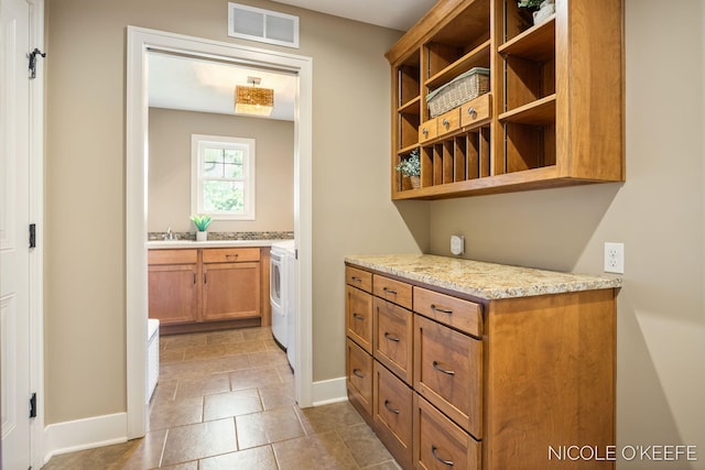 7150 Limerick Ln SW, Byron Center, MI 49315 - kitchen featuring open shelves, washer / clothes dryer, brown cabinets, and light stone countertops