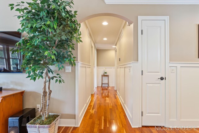 7150 Limerick Ln SW, Byron Center, MI 49315 - hall featuring a decorative wall, arched walkways, crown molding, wainscoting, and light wood-style floors
