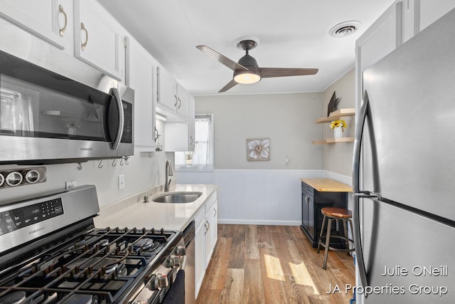 1035 Eastern Ave NE, Grand Rapids, MI 49503 - kitchen featuring stainless steel appliances, wood finished floors, light countertops, white cabinetry, and a ceiling fan