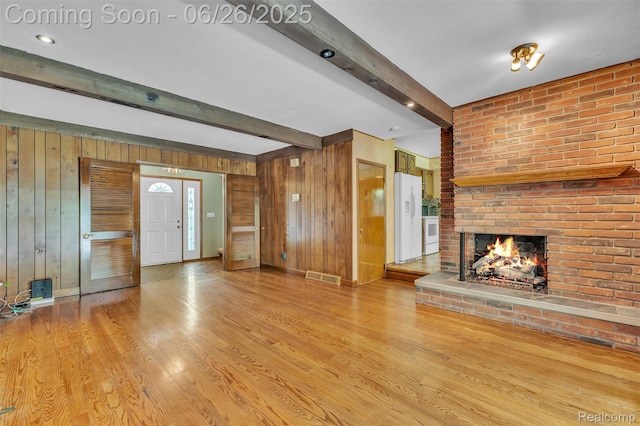 1840 Glen Iris Dr, Commerce Twp, MI 48382 - unfurnished living room featuring wood walls, beamed ceiling, a fireplace, and light wood-style flooring