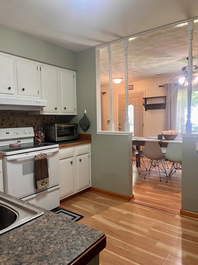 5213 Crocus Ave, Lansing, MI 48911 - kitchen featuring under cabinet range hood, white electric range oven, dark countertops, and light wood-style floors