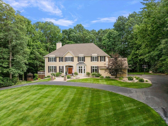 4608 Old Grand River Trl NE, Ada, MI 49301 - colonial inspired home with curved driveway, a chimney, a front lawn, and a storage unit