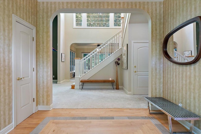 4608 Old Grand River Trl NE, Ada, MI 49301 - foyer entrance with wallpapered walls, arched walkways, wood finished floors, and stairway