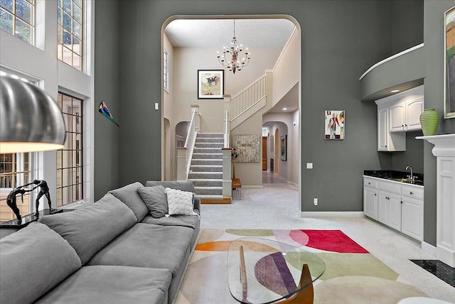 4608 Old Grand River Trl NE, Ada, MI 49301 - living room featuring arched walkways, a towering ceiling, light colored carpet, stairway, and a chandelier