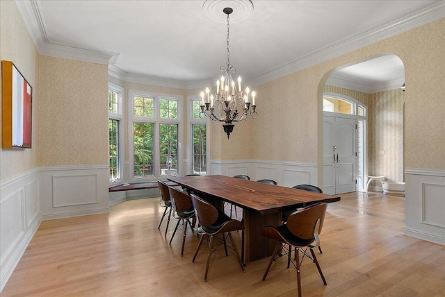 4608 Old Grand River Trl NE, Ada, MI 49301 - dining area featuring arched walkways, a chandelier, a decorative wall, wainscoting, and wallpapered walls