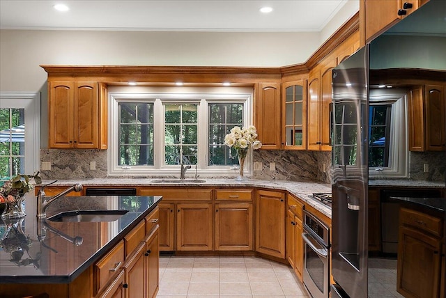 4608 Old Grand River Trl NE, Ada, MI 49301 - kitchen with stainless steel oven, dark stone countertops, brown cabinetry, and crown molding