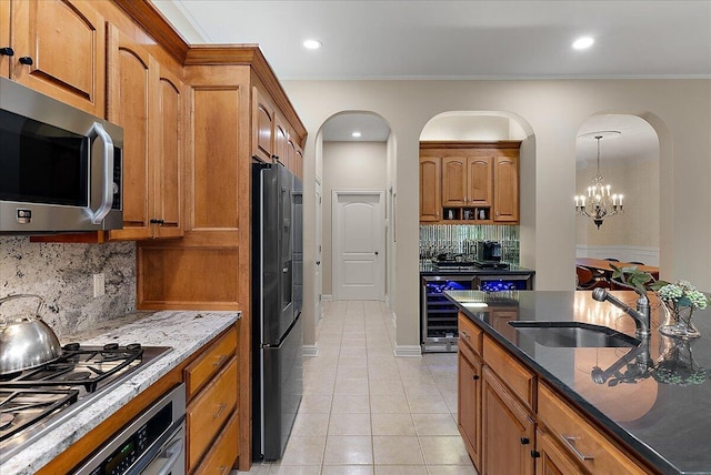 4608 Old Grand River Trl NE, Ada, MI 49301 - kitchen with stainless steel appliances, arched walkways, brown cabinets, and recessed lighting