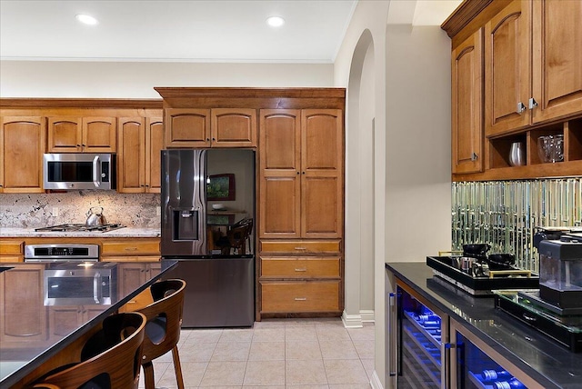 4608 Old Grand River Trl NE, Ada, MI 49301 - kitchen featuring stainless steel appliances, beverage cooler, arched walkways, decorative backsplash, and light tile patterned floors