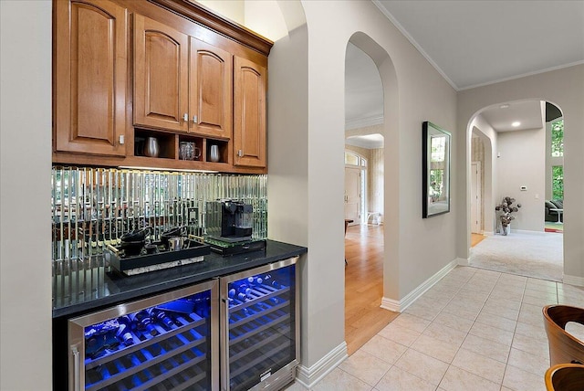 4608 Old Grand River Trl NE, Ada, MI 49301 - indoor bar with wine cooler, crown molding, arched walkways, and light tile patterned floors