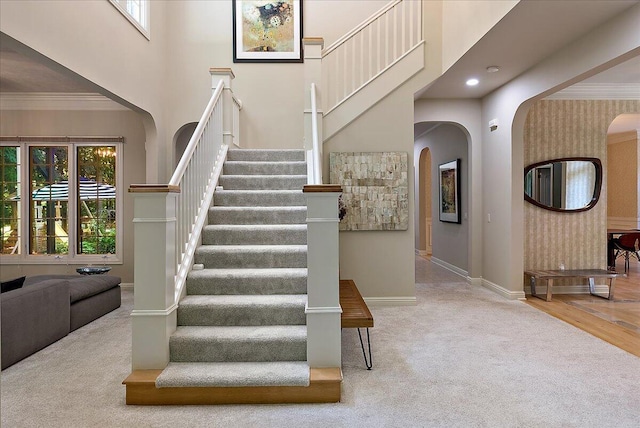 4608 Old Grand River Trl NE, Ada, MI 49301 - stairway with arched walkways, carpet floors, a towering ceiling, wallpapered walls, and crown molding