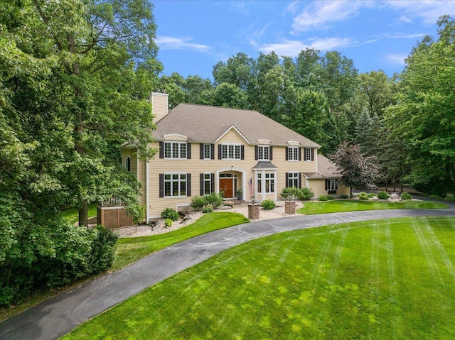 4608 Old Grand River Trl NE, Ada, MI 49301 - colonial home featuring a chimney, a front lawn, and asphalt driveway