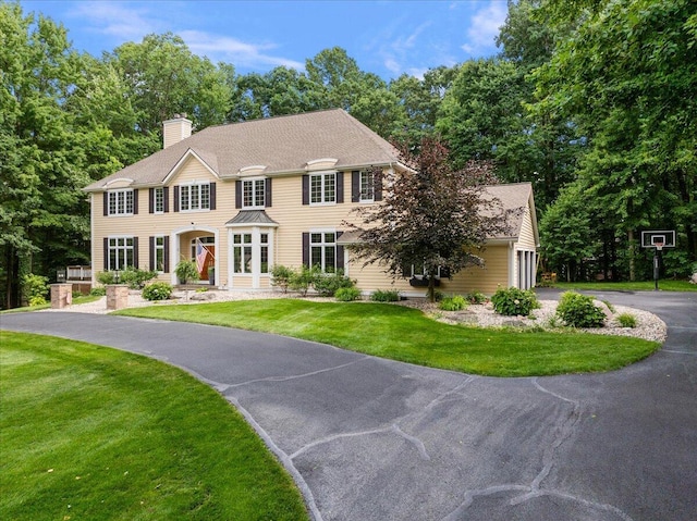 4608 Old Grand River Trl NE, Ada, MI 49301 - colonial inspired home with asphalt driveway, a front lawn, a chimney, and roof with shingles