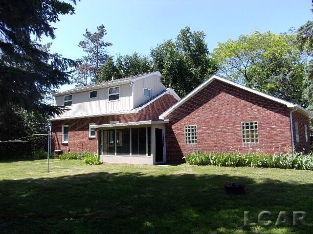 9981 W Mulberry Rd, Morenci, MI 49256 - back of property with a lawn, a sunroom, and brick siding