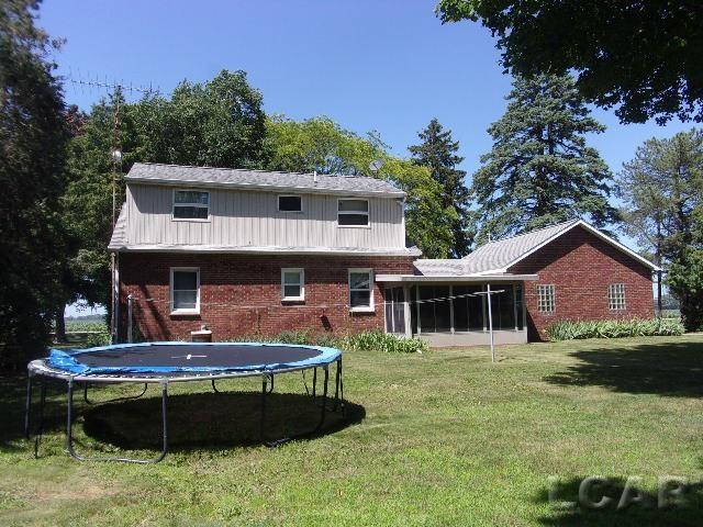 9981 W Mulberry Rd, Morenci, MI 49256 - rear view of property featuring a trampoline, a lawn, brick siding, and a sunroom