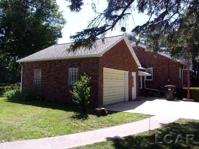 9981 W Mulberry Rd, Morenci, MI 49256 - view of side of home with brick siding, a lawn, an attached garage, concrete driveway, and roof with shingles