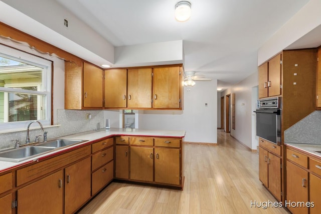 7970 Burlingame Ave SW, Byron Center, MI 49315 - kitchen with black oven, light wood-style floors, light countertops, and decorative backsplash