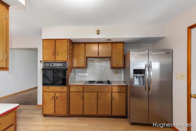 7970 Burlingame Ave SW, Byron Center, MI 49315 - kitchen with stainless steel refrigerator with ice dispenser, oven, brown cabinetry, stovetop, and light wood-style floors