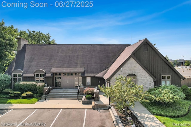 30715 River Crossing St, Bingham Farms, MI 48025 - view of front of property featuring uncovered parking, a chimney, board and batten siding, and roof with shingles