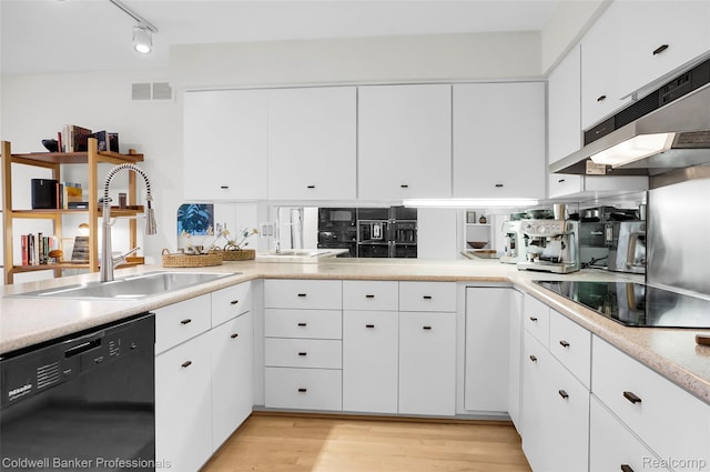 30715 River Crossing St, Bingham Farms, MI 48025 - kitchen featuring black appliances, under cabinet range hood, light countertops, light wood-type flooring, and white cabinetry