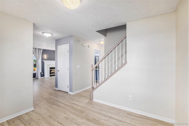 11632 Glen Mary Dr, Byron, MI 48418 - entrance foyer featuring light wood-style flooring, stairs, a textured ceiling, and a fireplace