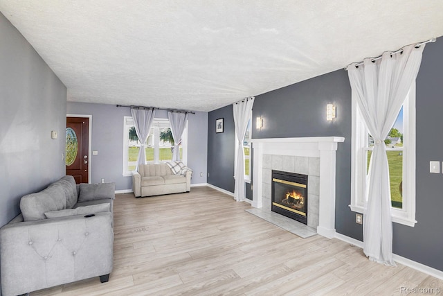 11632 Glen Mary Dr, Byron, MI 48418 - living area with a tile fireplace, light wood-type flooring, and a textured ceiling