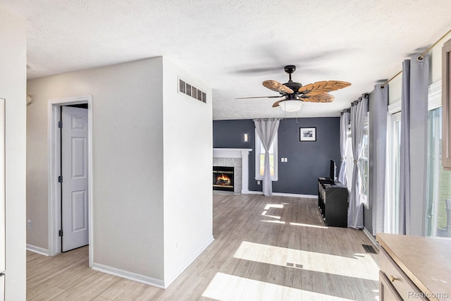 11632 Glen Mary Dr, Byron, MI 48418 - unfurnished living room featuring ceiling fan, a textured ceiling, a fireplace, and light wood-type flooring