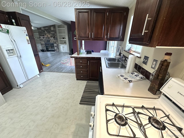 2652 Murphy Lake Rd, Silverwood, MI 48760 - kitchen featuring white appliances, light countertops, dark brown cabinets, and a fireplace