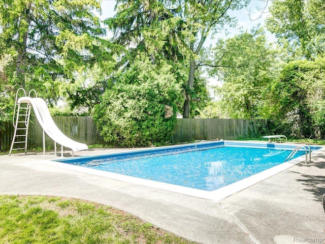 2815 Military St, Fort Gratiot, MI 48060 - view of pool with a water slide, a fenced backyard, view of wooded area, and a diving board
