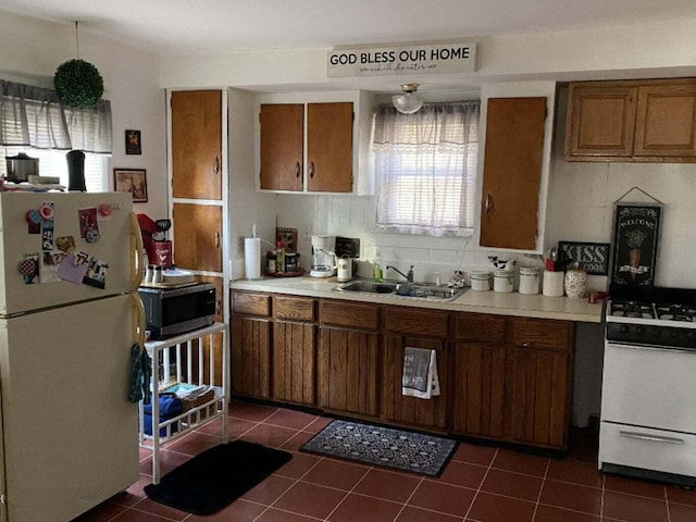 1925 Douglas Ave, Kalamazoo, MI 49007 - kitchen with white appliances, brown cabinets, dark tile patterned floors, and light countertops