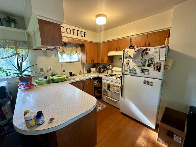 1805 Lakeshore Dr, Saint Joseph, MI 49085 - kitchen with white appliances, under cabinet range hood, brown cabinets, light countertops, and wood finished floors