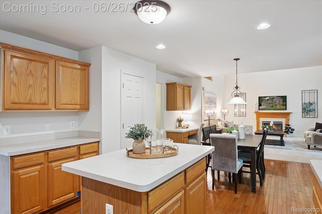 2538 Campbell Ct, Canton, MI 48188 - kitchen featuring open floor plan, hardwood / wood-style floors, light countertops, a glass covered fireplace, and a kitchen island